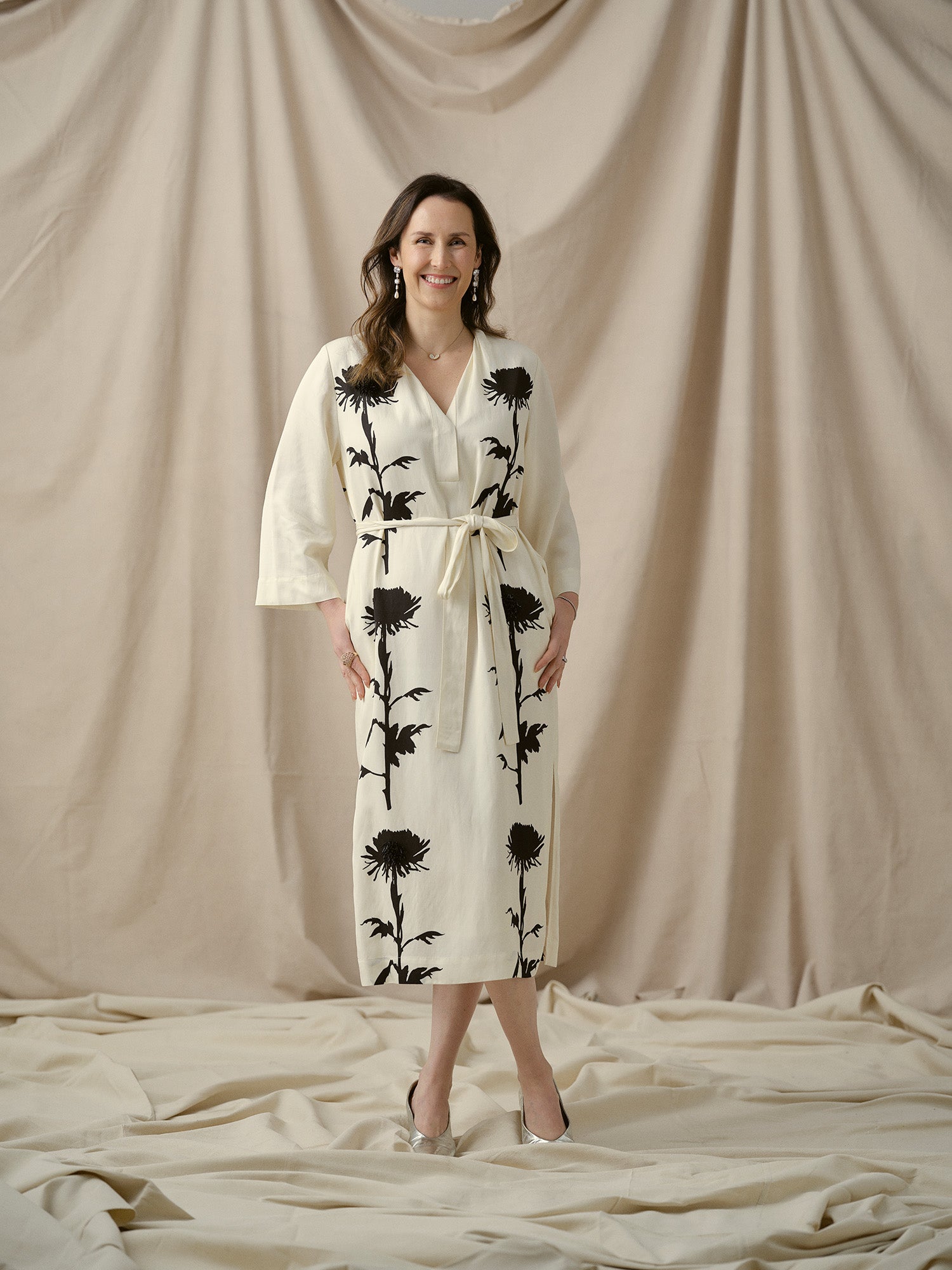 Suzi from Faith Jewels team posing on beige backdrop.