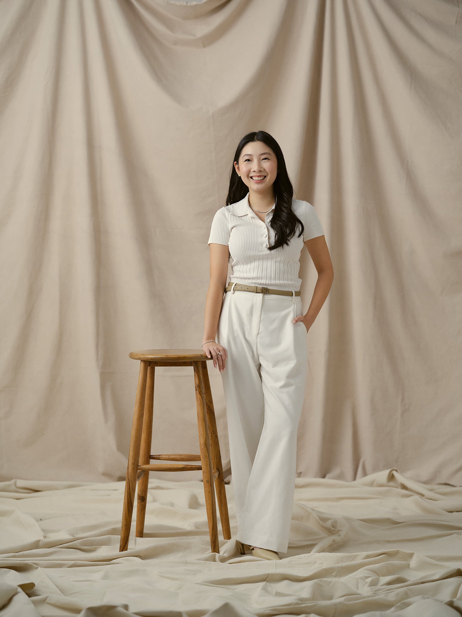 Claire from Faith Jewels team posing on beige backdrop.