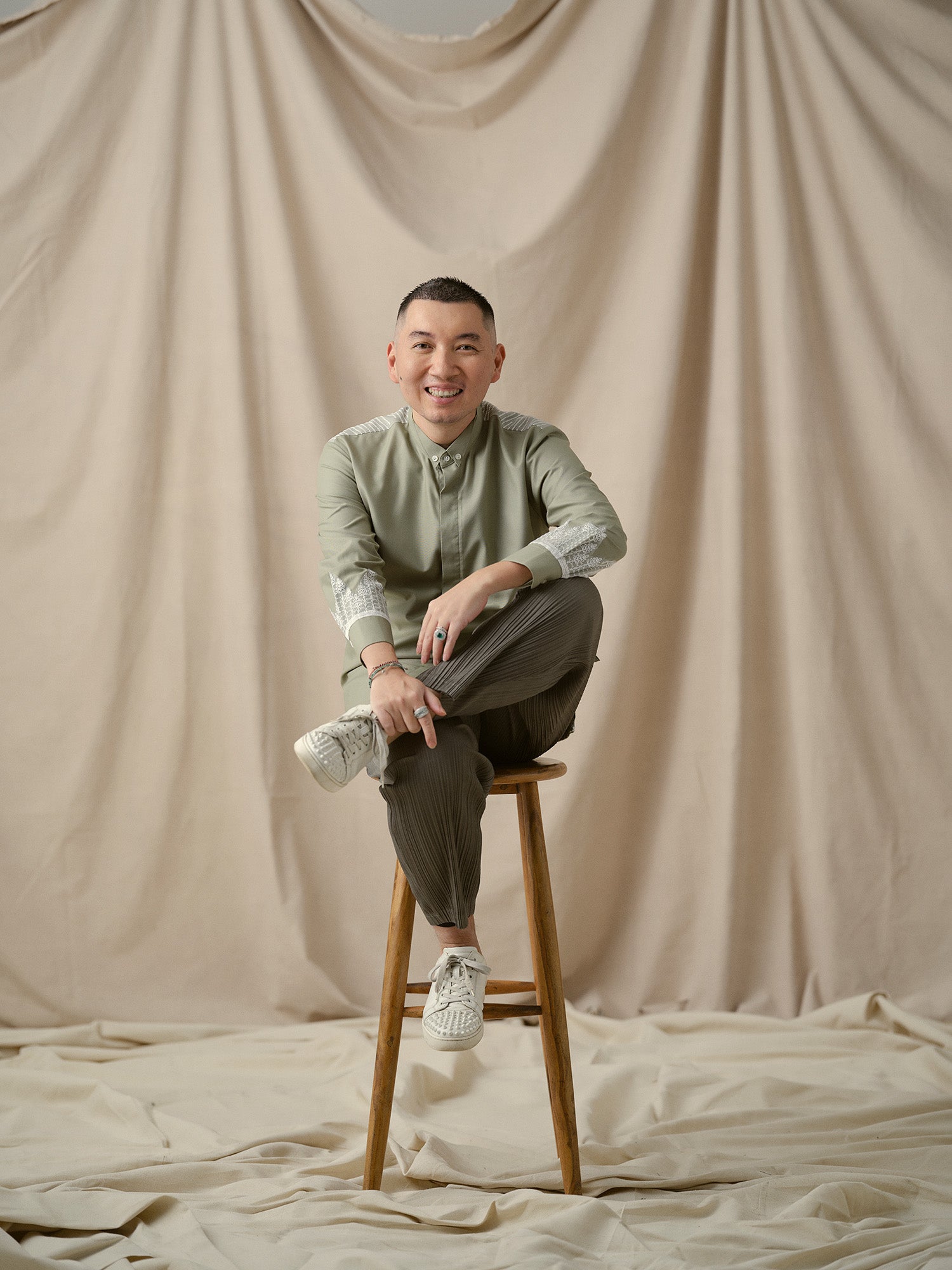William from Faith Jewels team posing on beige backdrop.