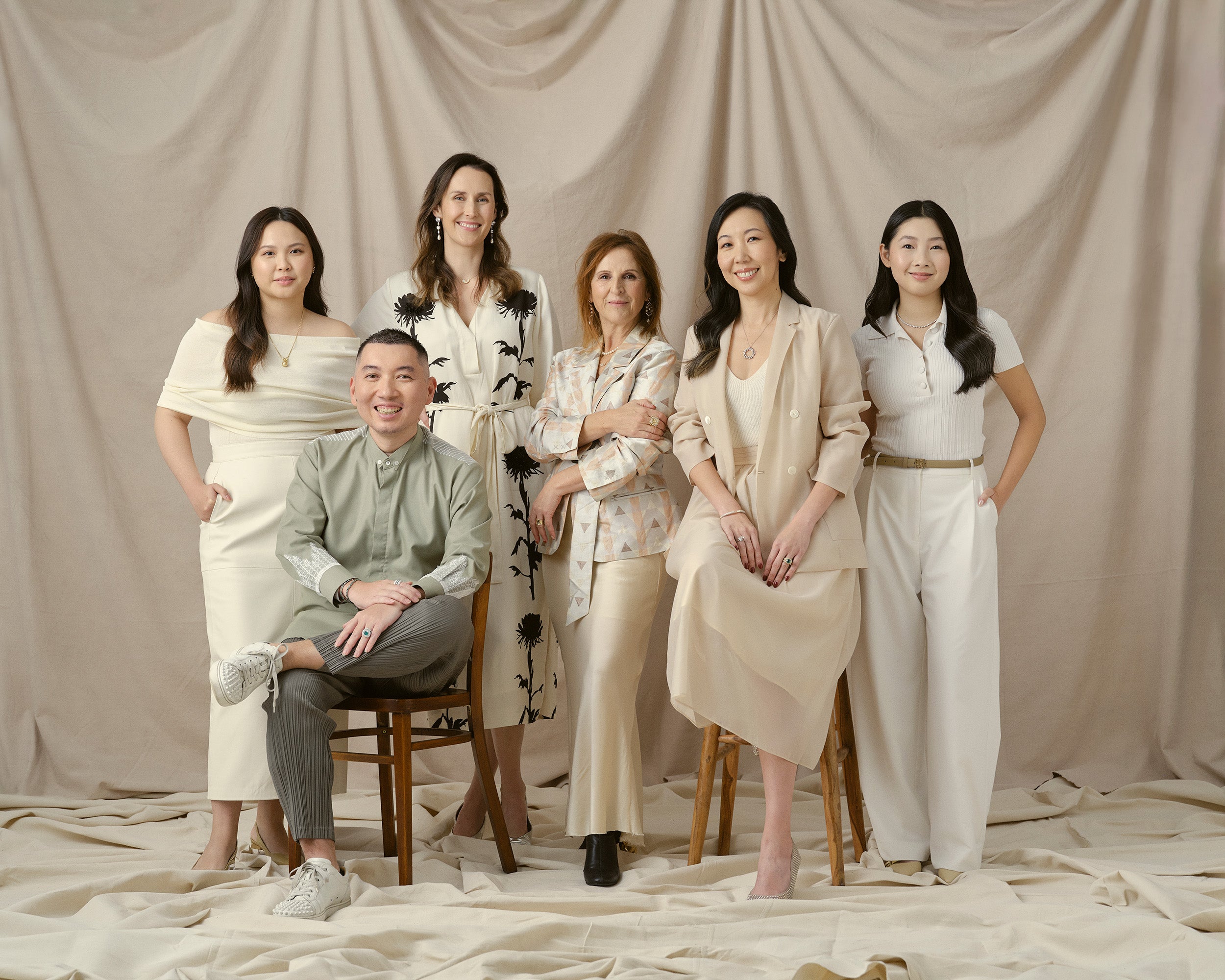 Group of Faith Jewels team posing together against a beige curtain background
