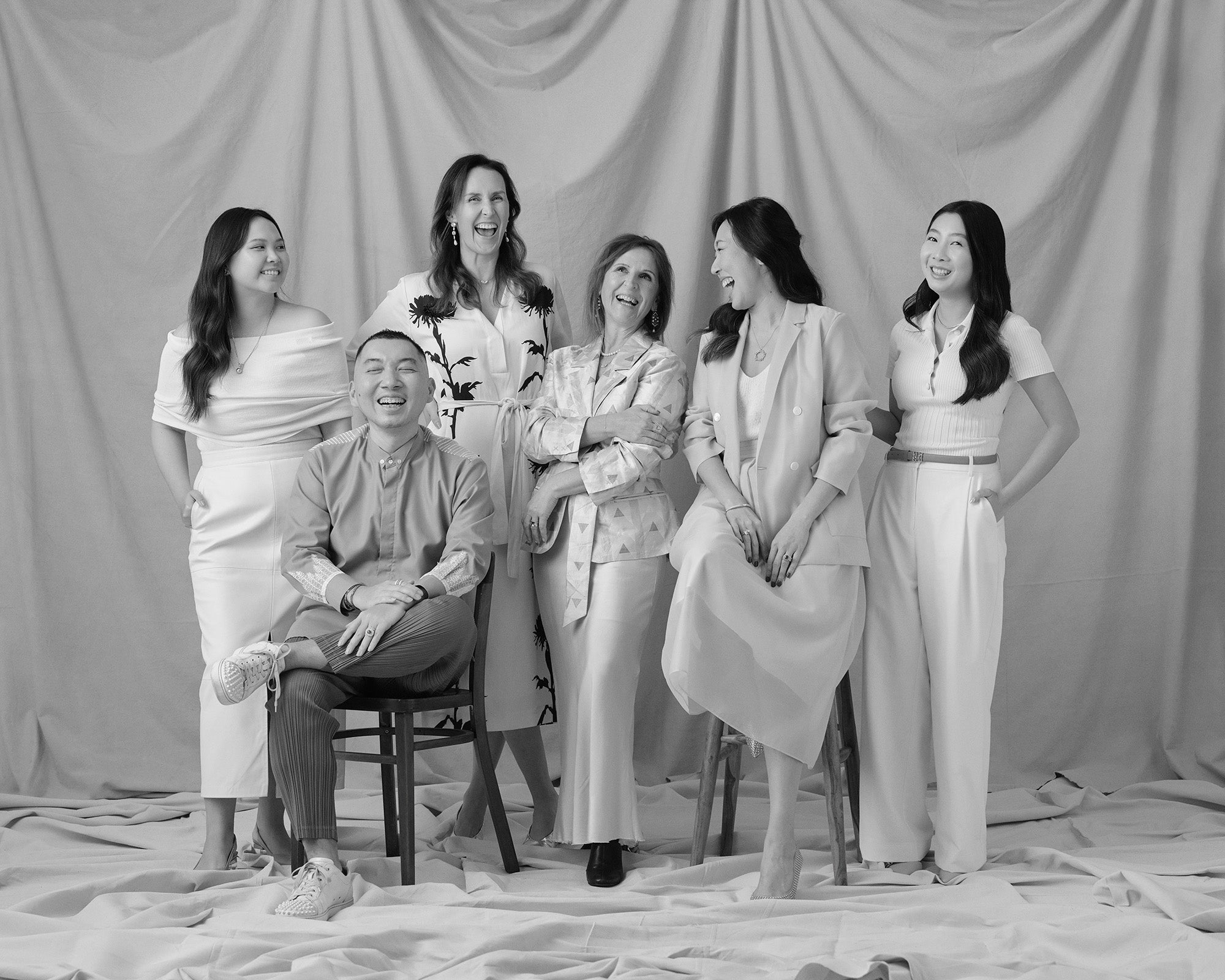 Group of Faith Jewels team posing together against a beige curtain background, in black and white