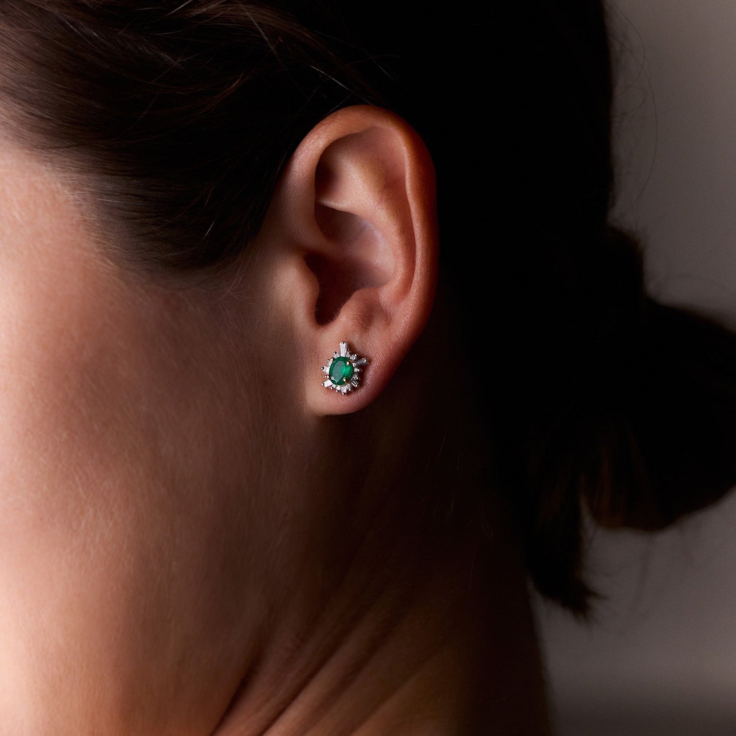 Oval-cut emerald sunburst earrings with white diamonds in yellow gold, radiant and elegant design, worn on model.
