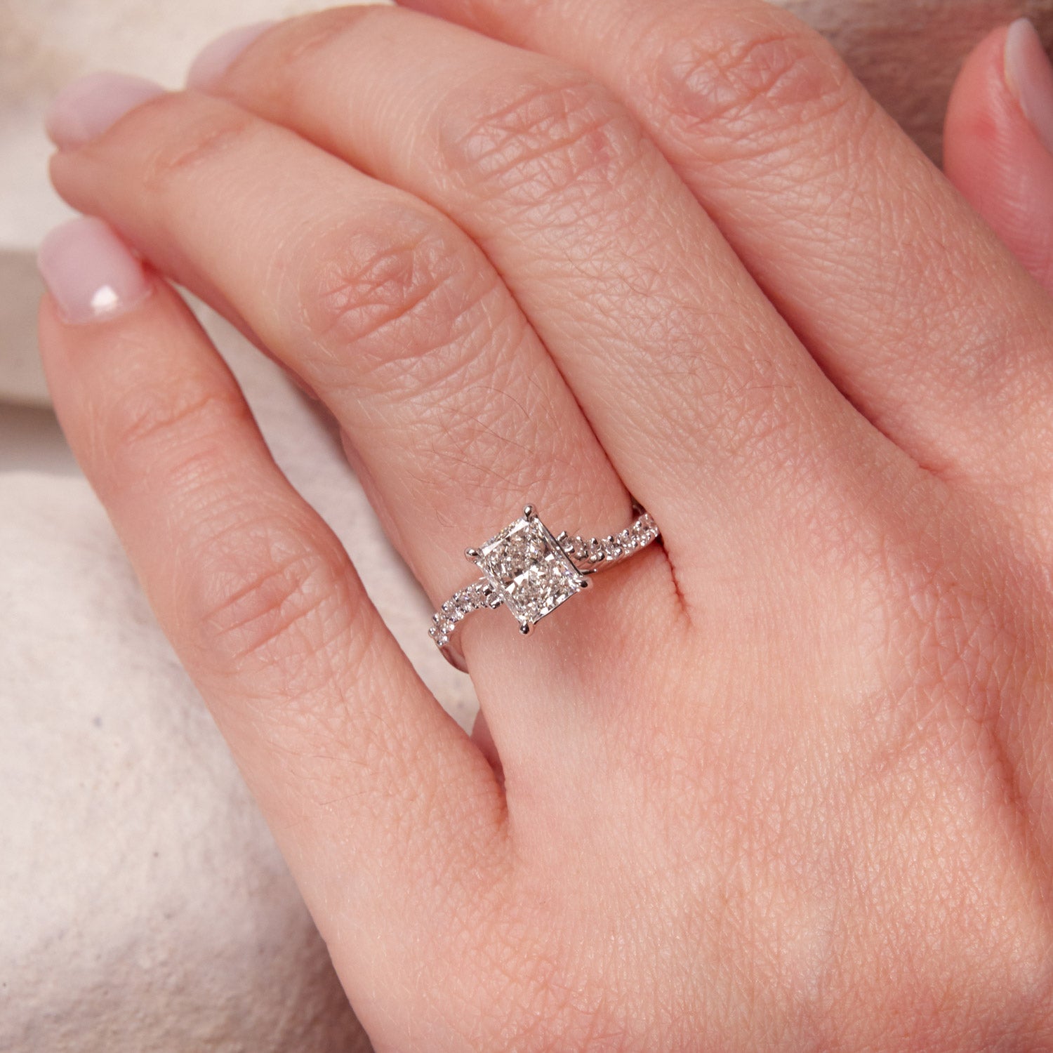 Faith Jewels Infinite Love Diamond ring featuring intertwined infinity loops, a radiant emerald-cut diamond center, and diamond-accented 18k white gold band