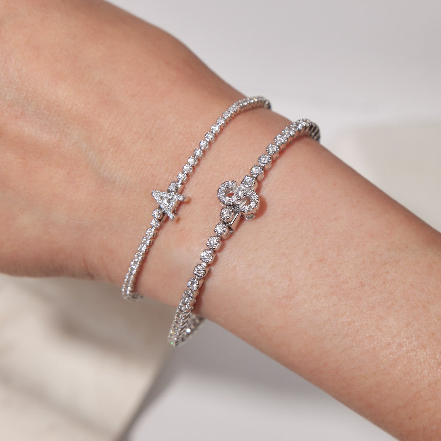 Faith Jewels bespoke initial diamond tennis bracelets in white gold, each featuring a unique clasp shaped as a letter A and S — set with round brilliant-cut diamonds