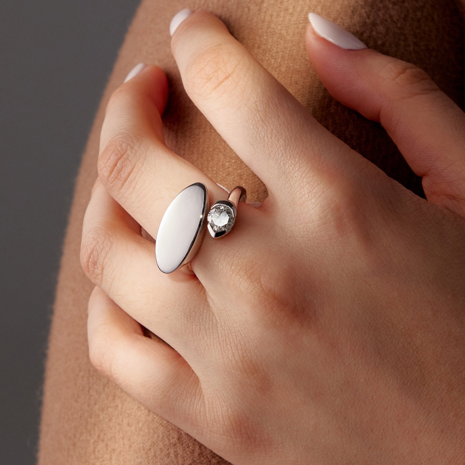 White gold ring with oval white stone and round diamond accent on hand