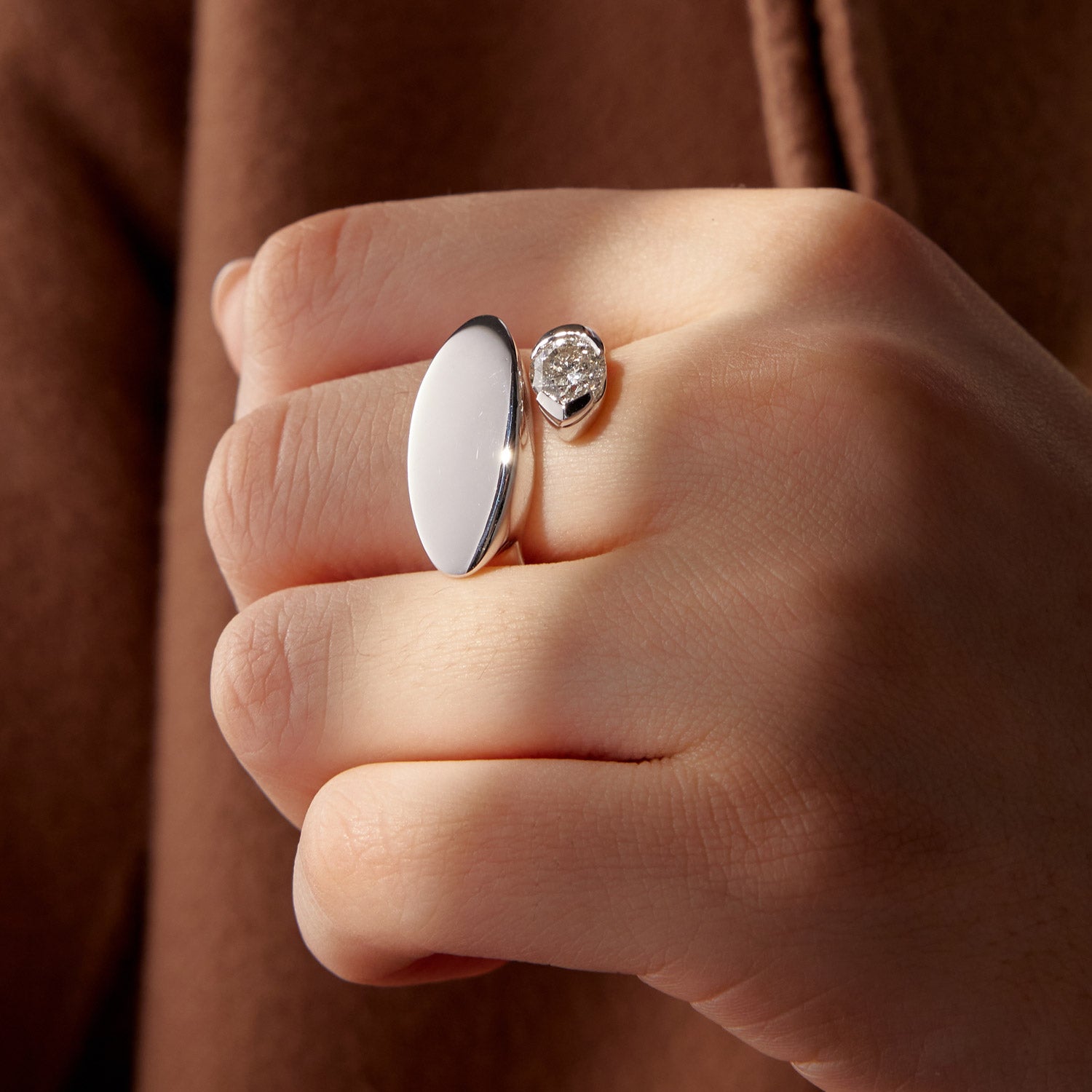 Two 18k white gold rings: one with oval white stone and one with pear-shaped diamond, worn on hand.
