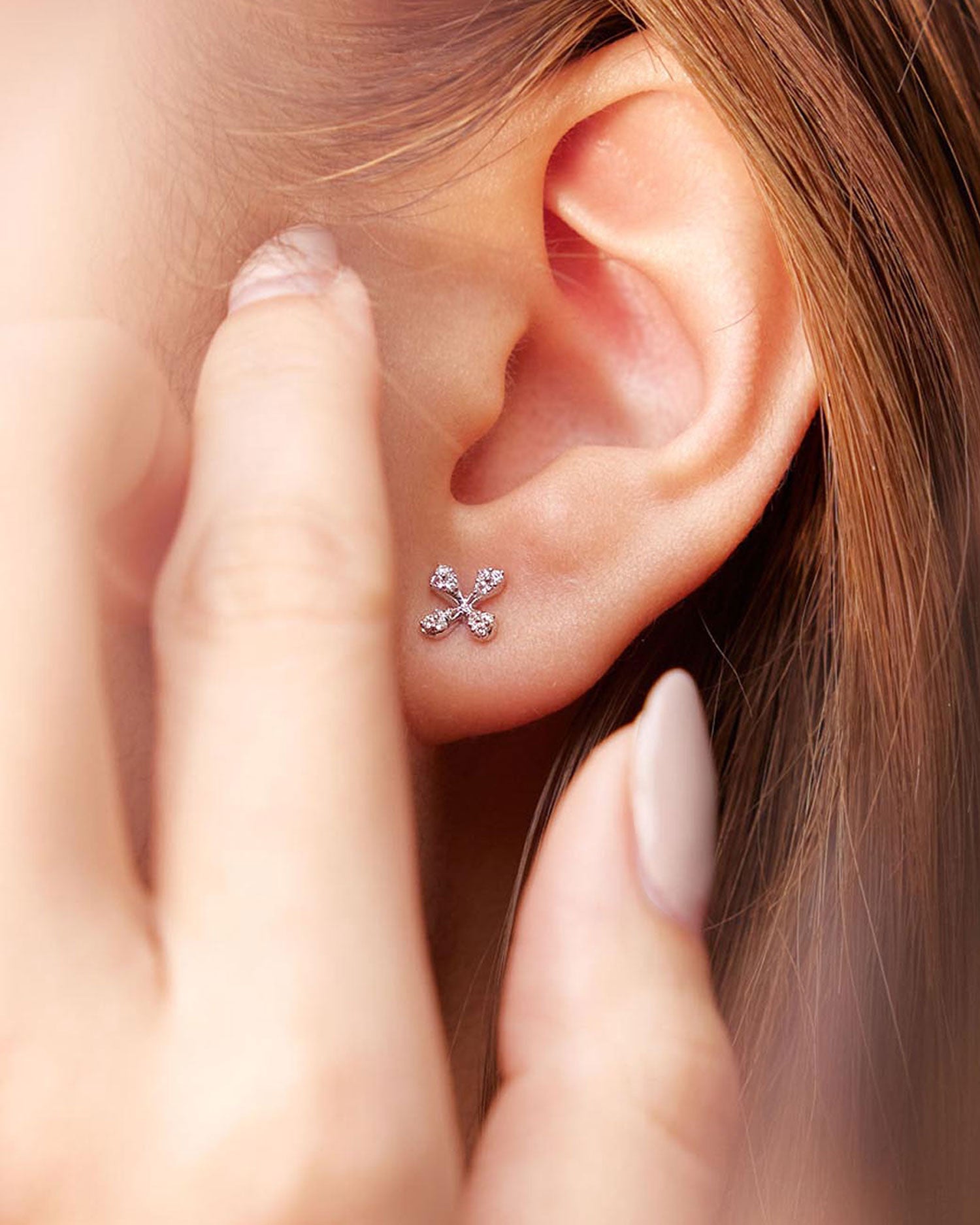 Mini Diamond Stud Earrings in 18k yellow gold with floral motif and diamonds on model.