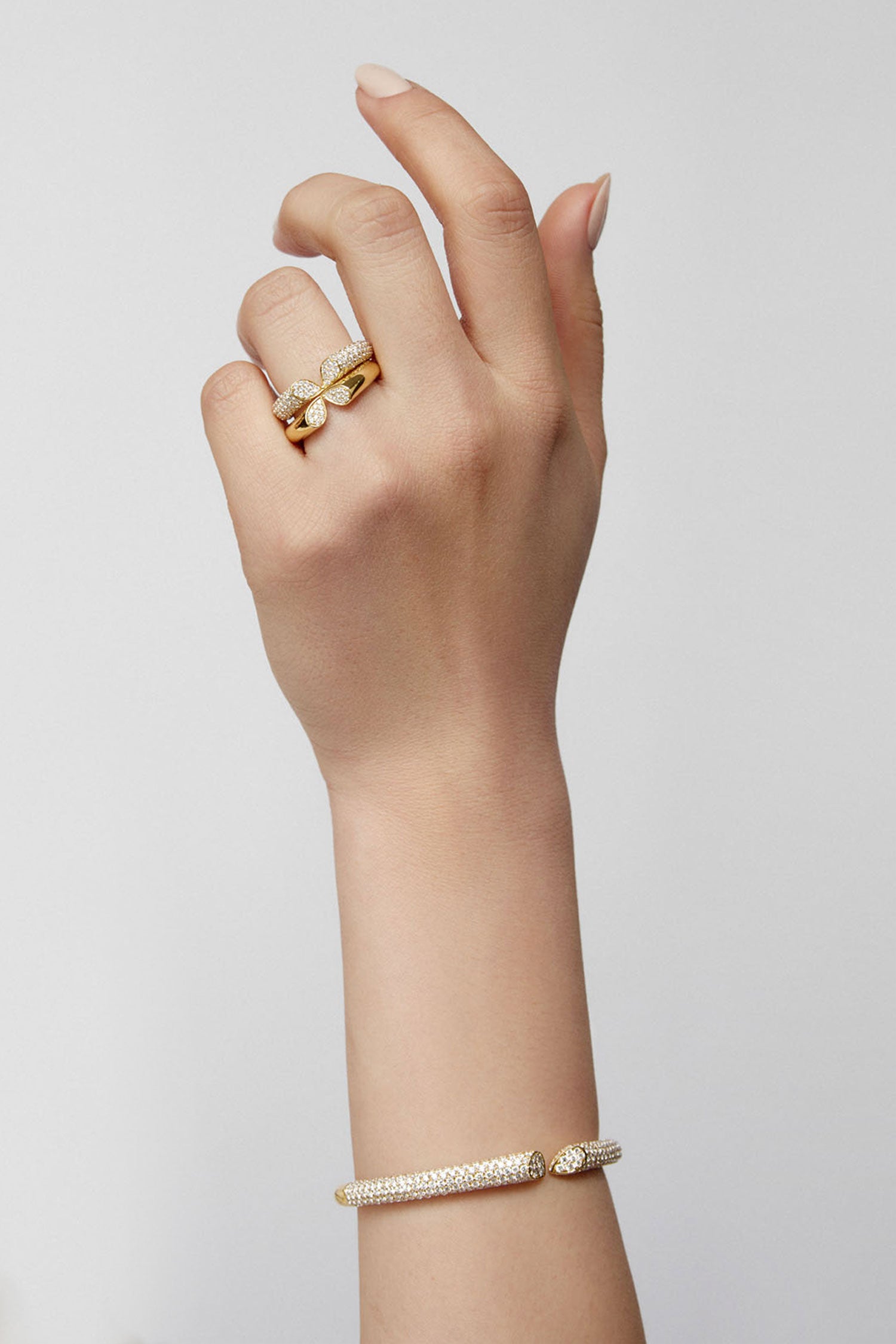 Faith Jewels 18k yellow gold bangle with 6.00ct pavé diamonds, featuring a heart-shaped lily petal design and secure hinge closure, worn with matching rings