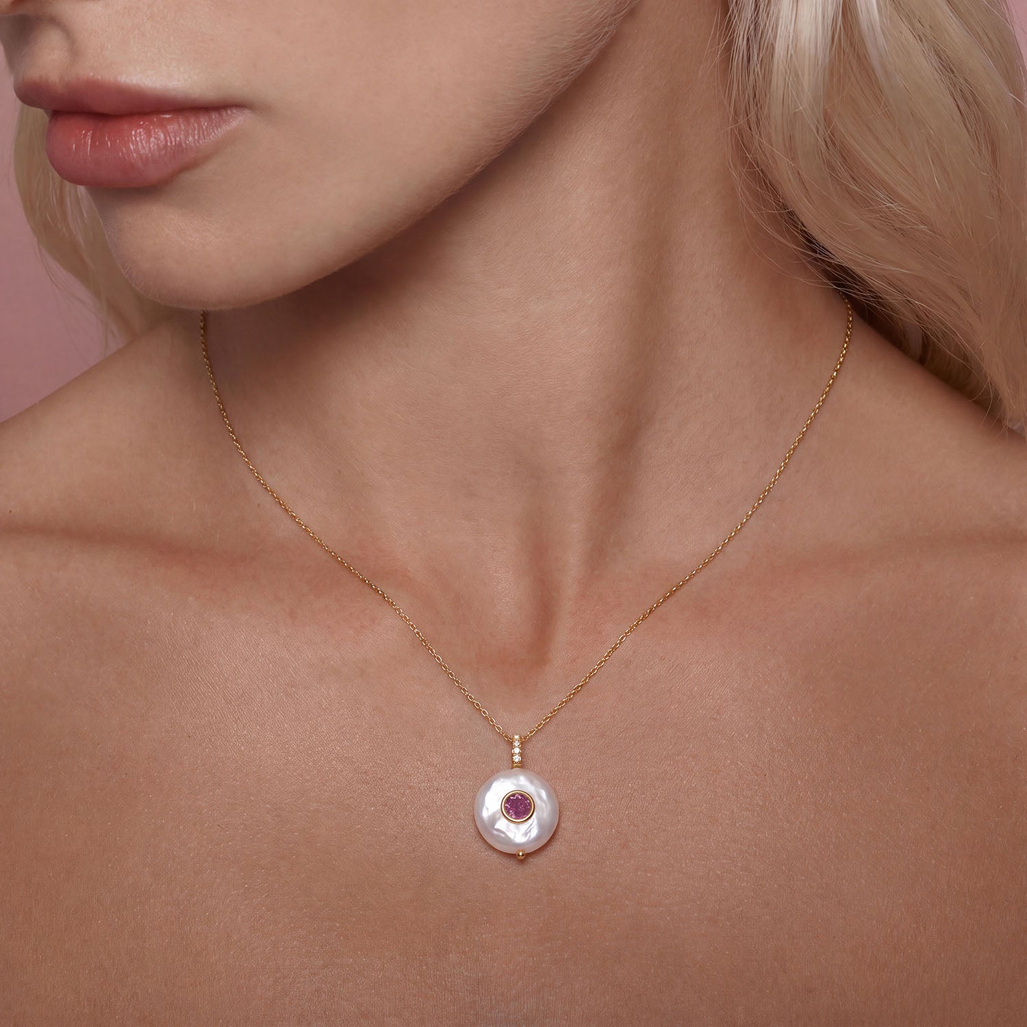 Gemdrops coin pearl and pink ruby charm in 9k yellow gold with a diamond-set bail, July birthstone, worn on model.