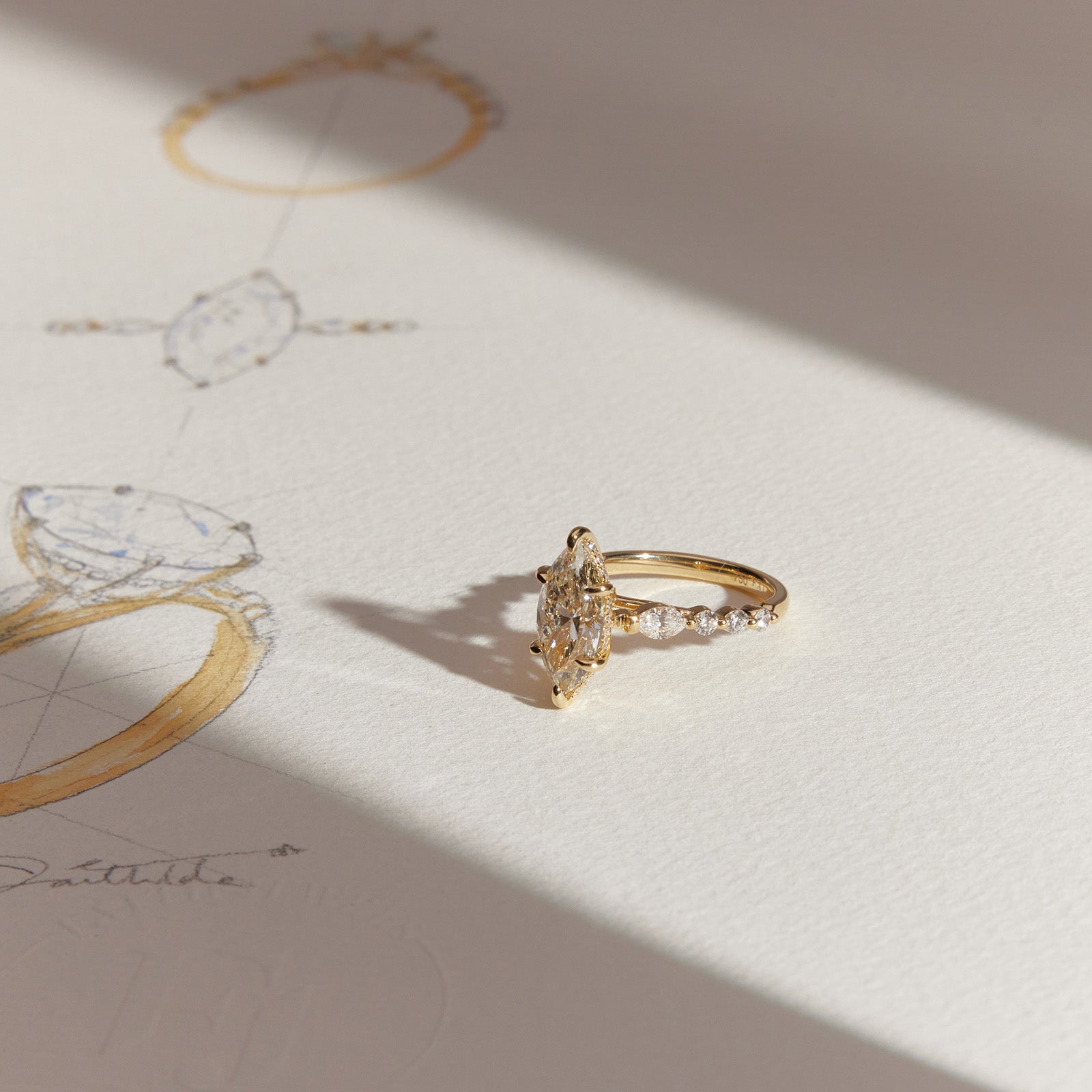 Marquise-cut diamond ring in yellow gold displayed on hand-sketched jewellery drawing