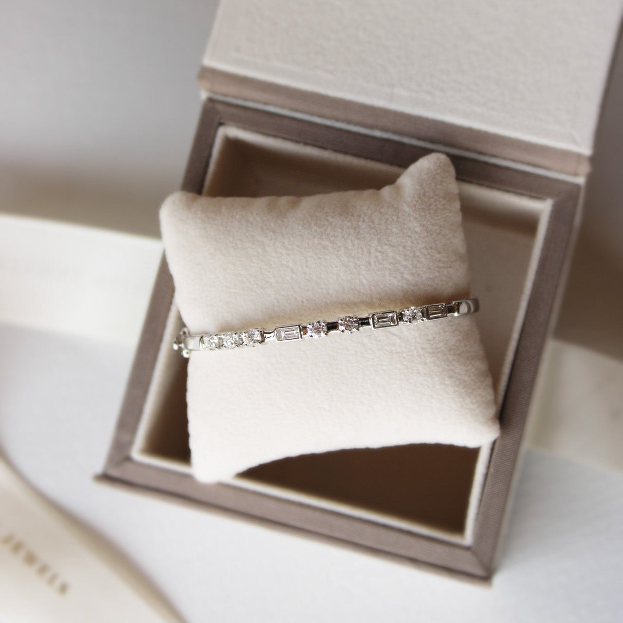 Elegant white gold bangle with round and baguette diamonds forming Morse code initials.