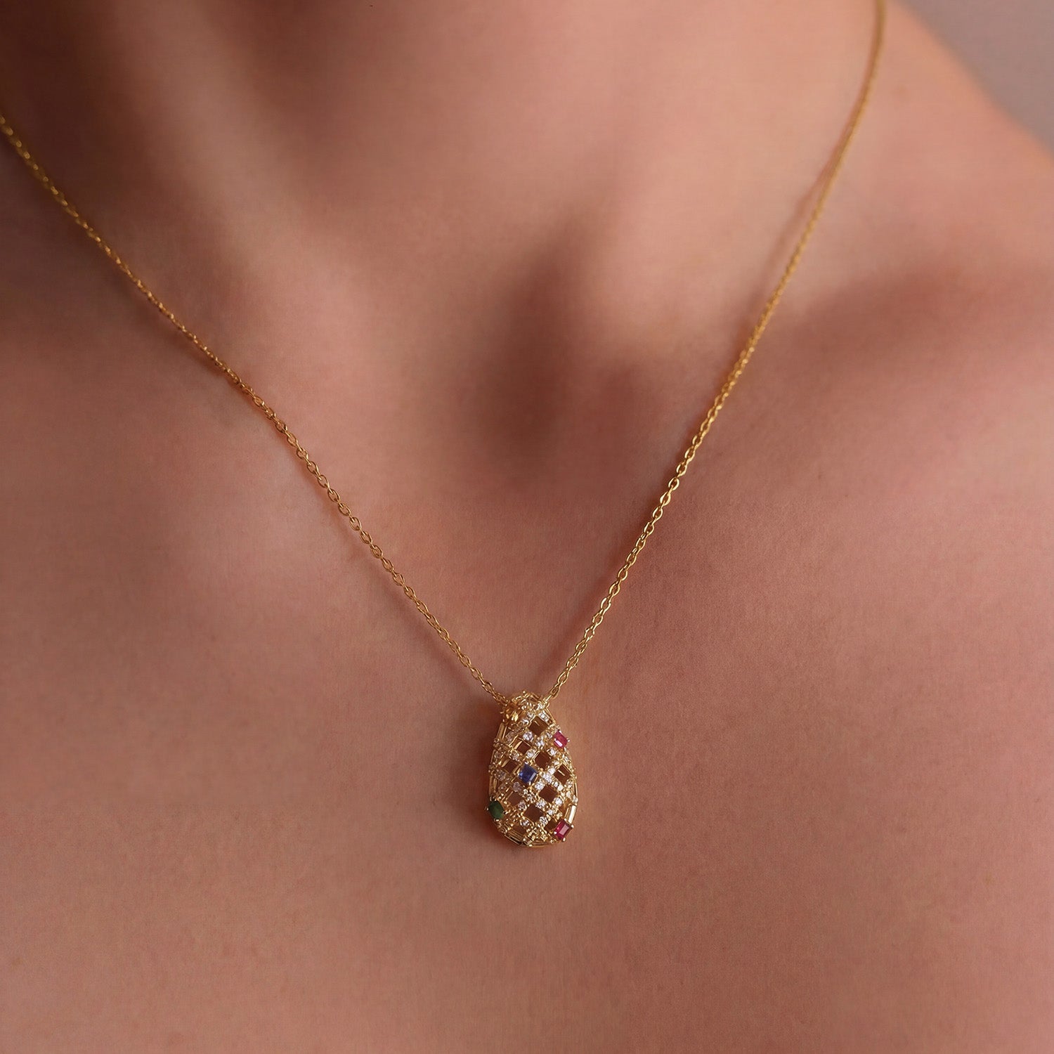 Yellow gold necklace with a teardrop-shaped pendant featuring colourful sapphire gemstones and diamonds, worn on model.