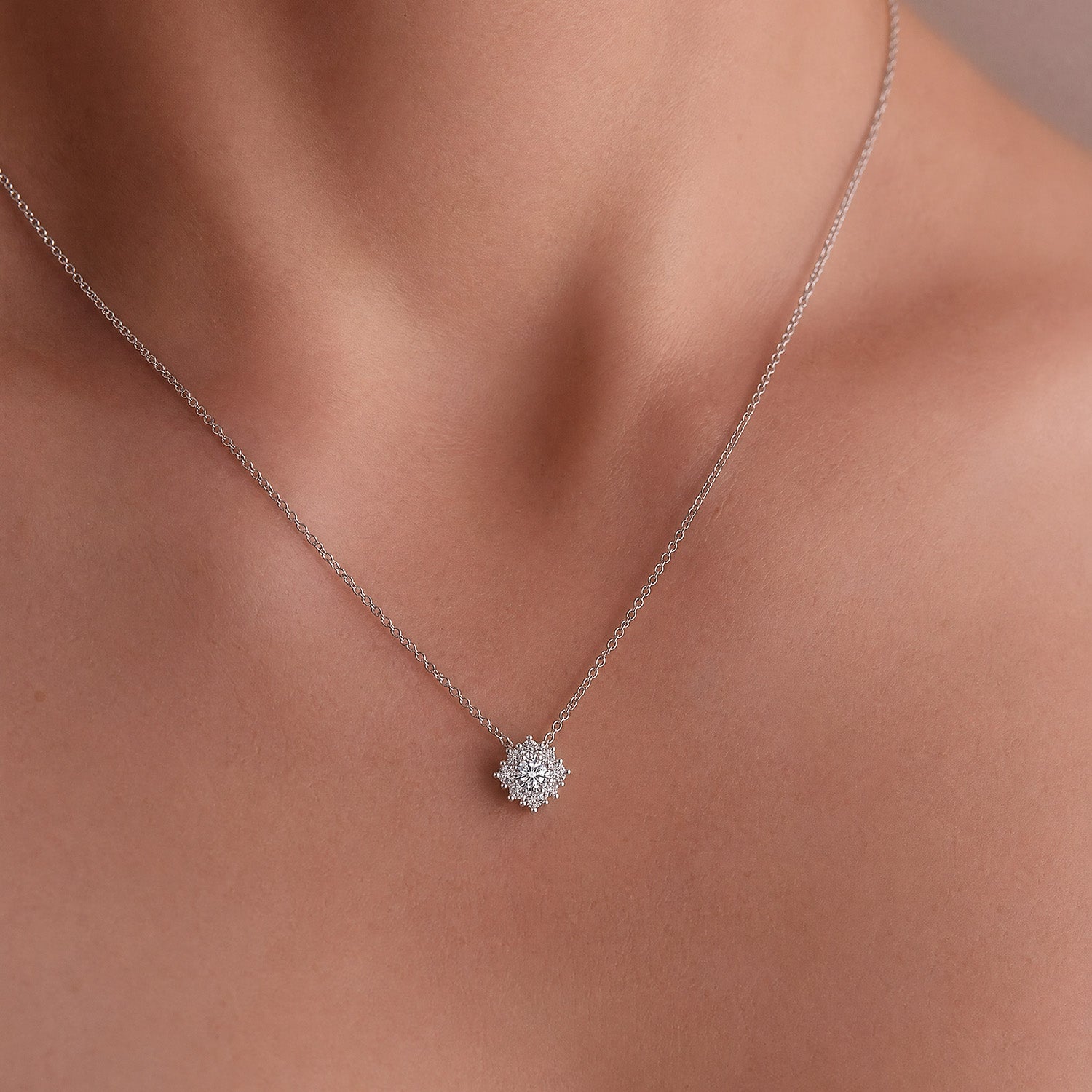 Mini snowflake diamond pendant necklace white gold, round diamond cluster snowflake design, worn on model.