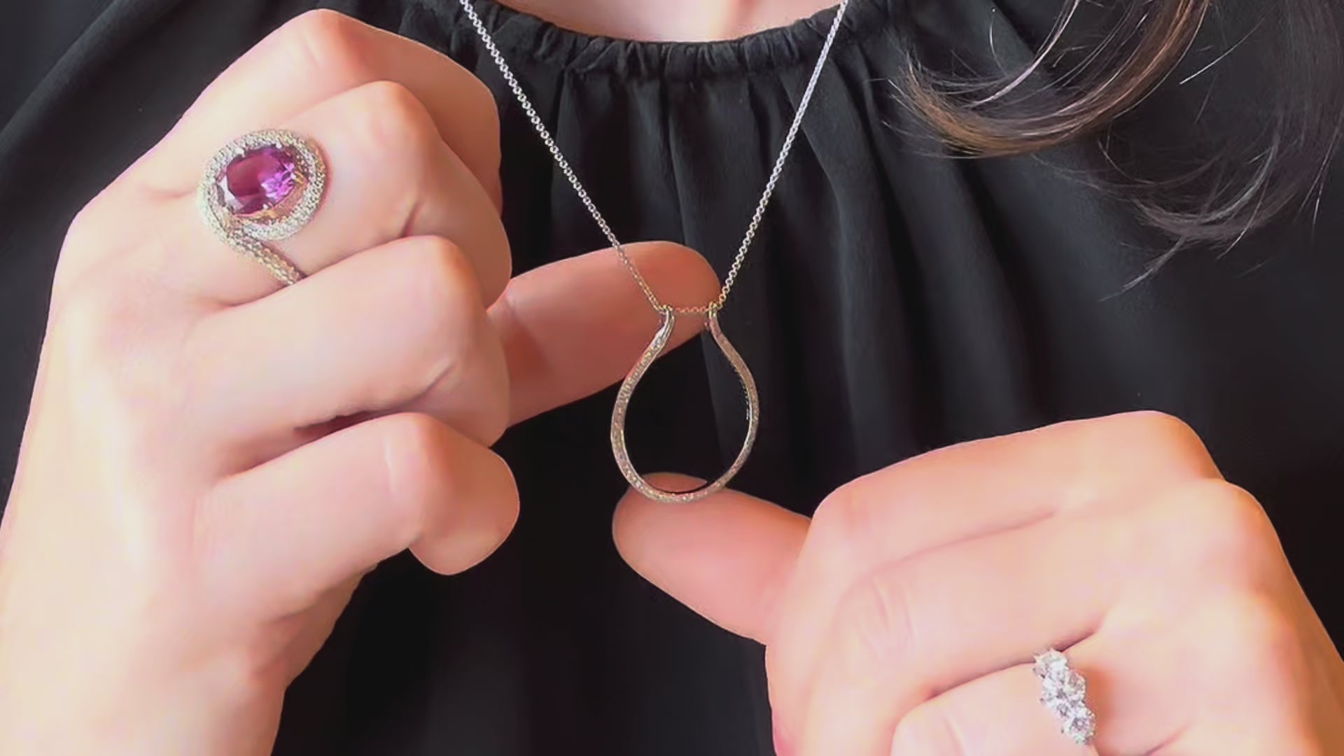 Faith Jewels Ring Holder Necklace demonstration — model showing how to secure a pink sapphire and diamond halo ring onto the white gold pavé diamond teardrop ring holder pendant necklace, three-stone diamond ring on opposite hand