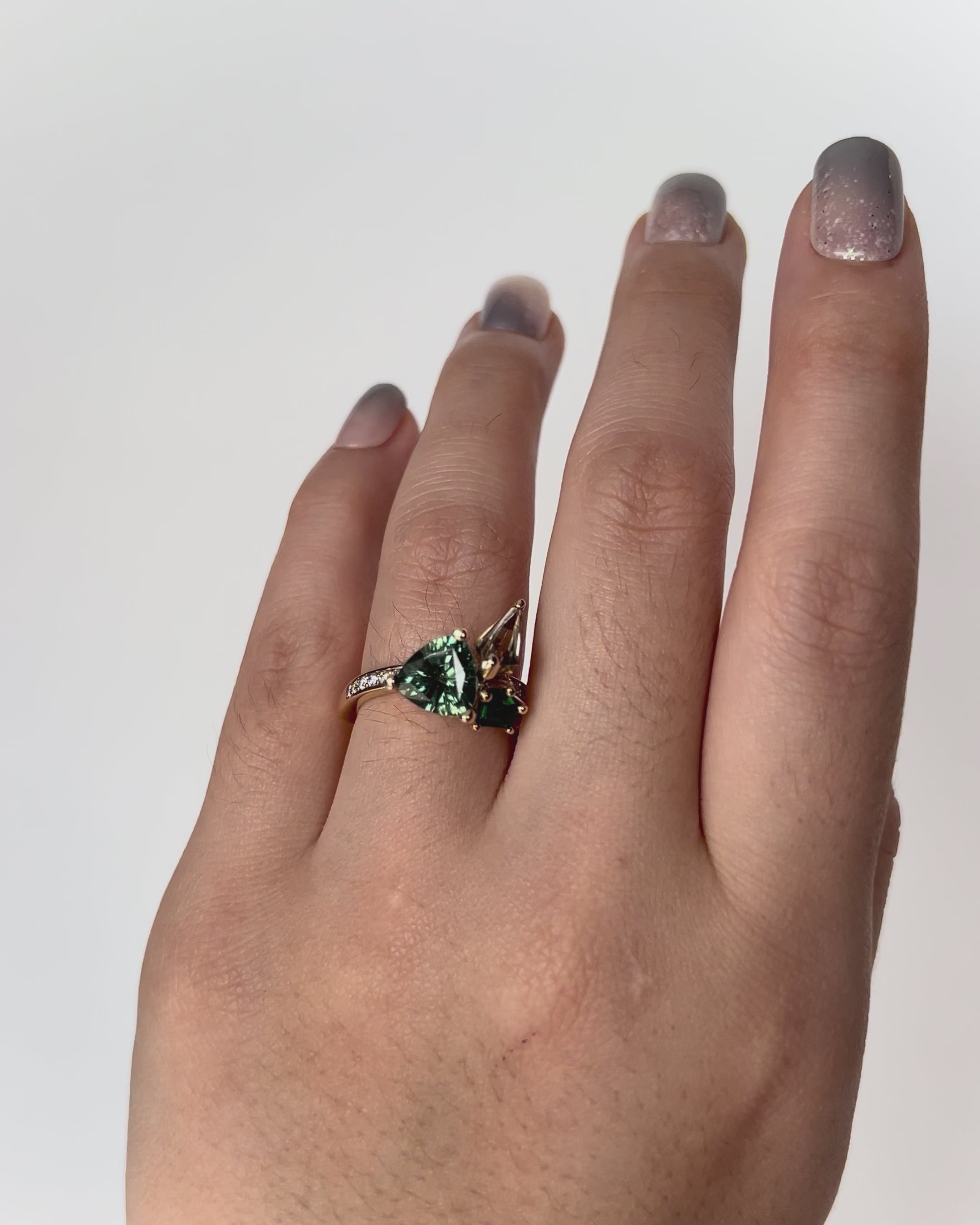 Multi-Green Bouquet Ring crafted in 9k yellow gold, featuring green sapphire, csarite, tsavorite and diamonds in a lush bouquet-inspired design, worn on model.