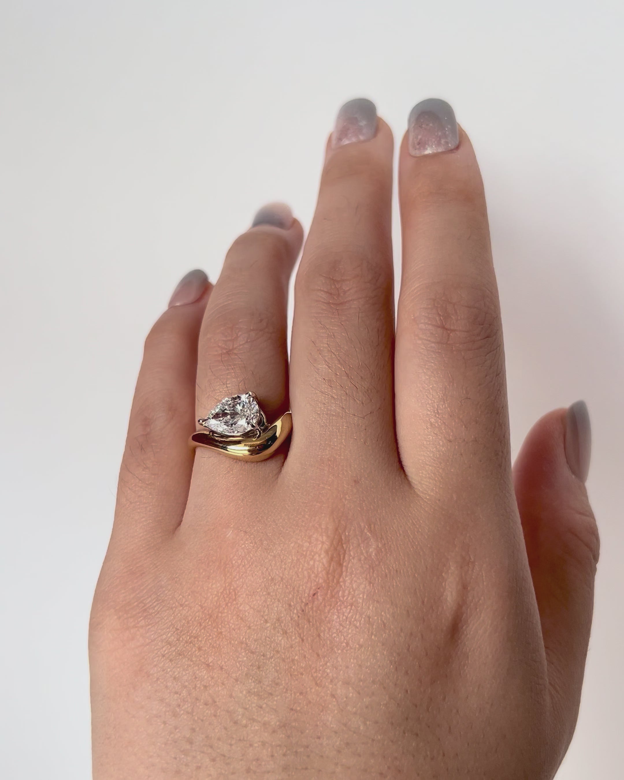 FJ Ring featuring a pear cut diamond set in a bold, curved yellow gold band with a sculptural, contemporary design.