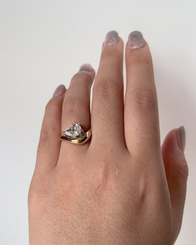 FJ Ring featuring a pear cut diamond set in a bold, curved yellow gold band with a sculptural, contemporary design.