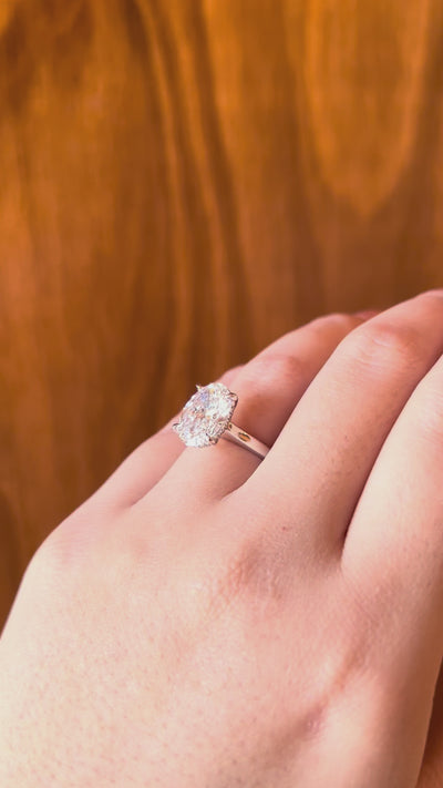 18k white gold engagement ring with 3.72ct oval-cut diamond, elegant band, combining timeless sophistication and contemporary design, worn on hand model.